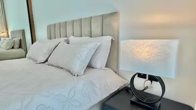 a bedroom with a bed with white pillows and a lamp at Luxury Apartment in Binghatti Amber in Dubai