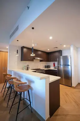 a kitchen with a counter with stools and a refrigerator at Modern 1BR 4 guest apartment World Trade Center in Dubai
