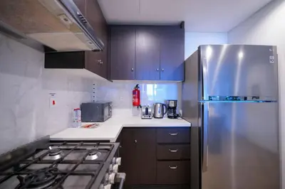 a kitchen with a stainless steel refrigerator and brown cabinets at Modern 1BR 4 guest apartment World Trade Center in Dubai
