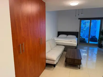 a living room with a cabinet and a couch and a bed at Modern Studio in Damac Park Tower - Near Dubai Mall & Metro in Dubai