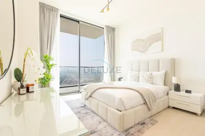 a white bedroom with a bed and a large window at High-Floor 1BR with Balcony Overlooking the Lake, Minutes from the Park, Binghatti Onyx, Jumeirah Village Circle by Deluxe Holiday Homes in Dubai