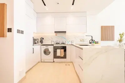 a white kitchen with a washer and dryer at High-Floor 1BR with Balcony Overlooking the Lake, Minutes from the Park, Binghatti Onyx, Jumeirah Village Circle by Deluxe Holiday Homes in Dubai