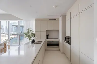 a kitchen with white cabinets and a large window at Luxury 3BR & Maid - Canal View - Near Downtown in Dubai
