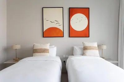two beds in a room with three pictures on the wall at Luxury 3BR & Maid - Canal View - Near Downtown in Dubai