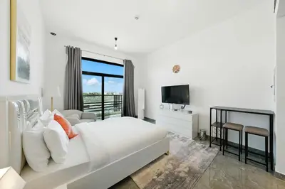 a white bedroom with a large bed and a television at Luxury Retreat in Arjan with Refined Living in Dubai