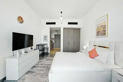 a white bedroom with a large white bed and a flat screen tv at Luxury Retreat in Arjan with Refined Living in Dubai