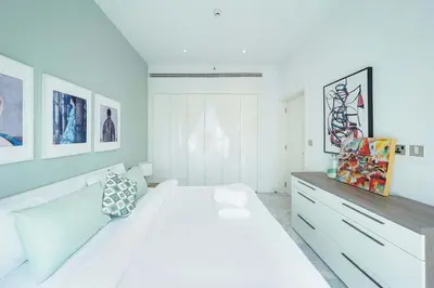 a white bedroom with a large bed and some pictures at Designer 1BR Retreat With Stunning Canal View in Dubai