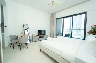 a white bedroom with a large bed and a table at AWS Holiday Homes - Relaxing Stylish Studio in Dubai