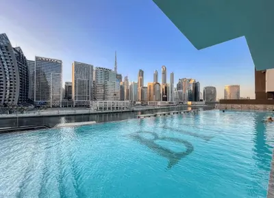 a large swimming pool with a city in the background at AWS Holiday Homes - Relaxing Stylish Studio in Dubai