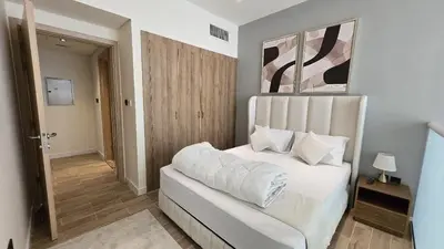a bedroom with a bed with white sheets and pillows at Stylish 1BR Loft TH in Rukan in Dubai