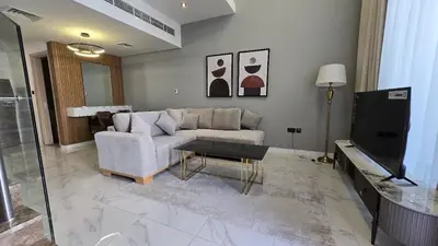 a living room with a couch and a tv at Stylish 1BR Loft TH in Rukan in Dubai
