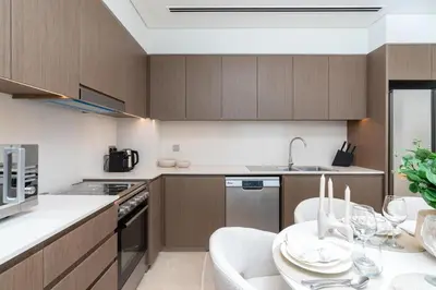 a kitchen with wooden cabinets and a table with chairs at Grande, Luxurious 2 BR, Burj Khalifa & Fountain view in Dubai