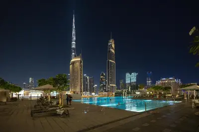 a swimming pool with a city skyline at night at Maison Privee - Urban & Elegant Stay Just Steps from Burj Khalifa in Dubai
