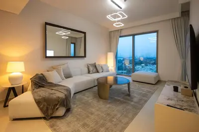 a living room with a white couch and a large window at Maison Privee - Urban & Elegant Stay Just Steps from Burj Khalifa in Dubai