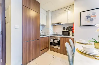 a kitchen with wooden cabinets and a dining table at High-Rise 2BR with Dubai Water Canal View, Quick Access to Downtown, Vera Tower, Business Bay by Deluxe Holiday Homes in Dubai