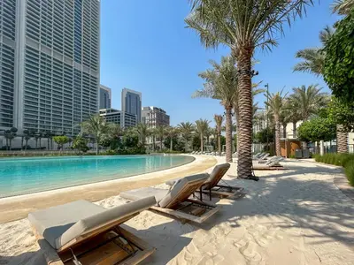 a swimming pool with chaise lounge chairs and palm trees at Elegant at Creek Beach Lotus 1BHK in Dubai