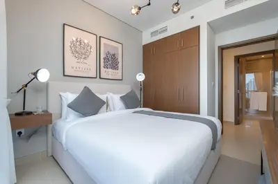 a bedroom with a large white bed and a wooden cabinet at Vogue Marina 52-42 Towers near Ain Dubai and JBR Beach, Two Bedroom Apartment with Balcony Canal and Skyline views, Access to all Amenities in Dubai