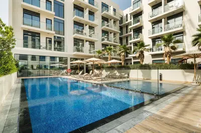 a swimming pool in front of a building at Luxurious JVC Studio Near Circle Mall & Parks in Dubai