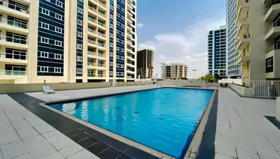 a swimming pool in the middle of a building with tall buildings at Studio with Balcony Facing the Community, Located Near Golf Clubs and Cricket Stadium, Royale Residence 1 , Dubai Sports City by Deluxe Holiday Homes in Dubai