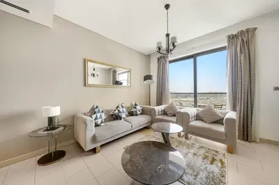 a living room with a couch and a table at Luxurious 2BR Apartment in Sobha Hartland Greens in Dubai