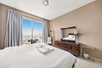 a bedroom with a bed and a desk and a mirror at Luxurious 2BR Apartment in Sobha Hartland Greens in Dubai