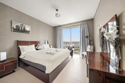 a bedroom with a large bed and a window at Luxurious 2BR Apartment in Sobha Hartland Greens in Dubai