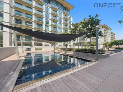 a swimming pool in front of a building at Luxurious 2BR Apartment in Sobha Hartland Greens in Dubai