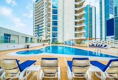 a swimming pool with lounge chairs and a building at The Dorra Bay Offers Stunning 2bedroom Duplex JBR Sea View Marina Canal view in Dubai