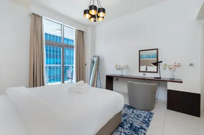 a white room with a bed and a desk and a window at Ahlan HH - Stylish Suite Heart of Business Bay Avanti Tower in Dubai