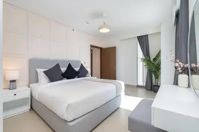 a white bedroom with a large bed and a table at Vogue Marina 52-42 Towers near Ain Dubai and JBR Beach, Two Bedroom Apartment with Balcony Canal and Skyline views, Access to all Amenities in Dubai
