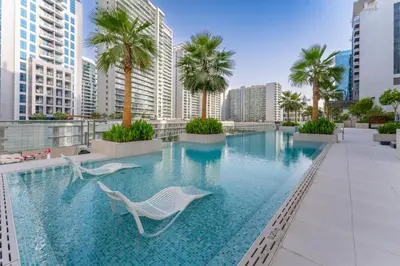 a swimming pool with chairs and palm trees on a building at Luxury Burj & Fountain View Retreat in Dubai