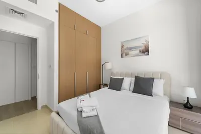 a bedroom with a large white bed and a couch at Stylish 2BR at Creek Grove Near Downtown in Dubai