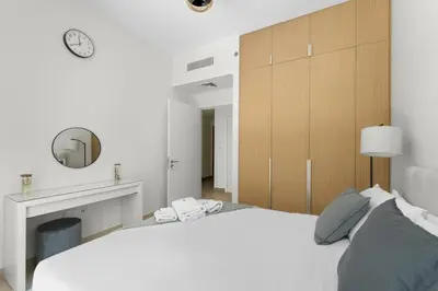 a white bedroom with a large bed and a mirror at Stylish 2BR at Creek Grove Near Downtown in Dubai