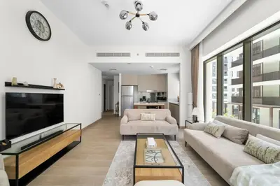 a living room with two couches and a large tv at Stylish 2BR at Creek Grove Near Downtown in Dubai