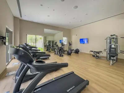 a gym with rows of exercise bikes and treadmills at Stylish 2BR at Creek Grove Near Downtown in Dubai