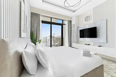 a white bedroom with a large bed and a tv at Farhad Azizi Residence Al Jaddaf in Dubai