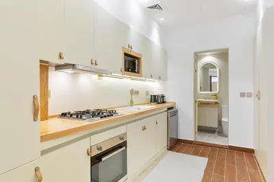 a kitchen with white cabinets and a stove top oven at Designer Loft Studio with top Amenities in JVC in Dubai