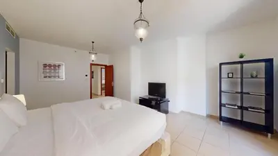 a bedroom with a large white bed and a television at Vacationer I Royale 3 Bedroom I Steps to JBR Beach I Jumeirah I Free Gym, Pool, Parking & Wi-Fi in Dubai
