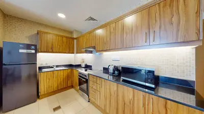 a kitchen with wooden cabinets and a stainless steel refrigerator at Vacationer I Premium 1 Bedroom I Canal View I Business Bay I Free Gym, Pool, Parking & Wi-Fi in Dubai