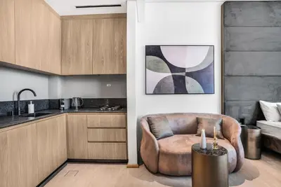 a living room with a chair and a kitchen at Stylish Studio in The Autograph in Dubai