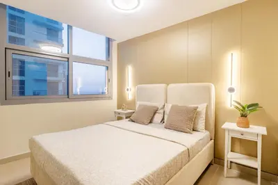 a bedroom with a bed with two tables and two windows at Luxury 3BHK in Dubai Marina DEC 1307 in Dubai