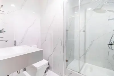 a white bathroom with a shower and a sink at Lux 3BHK in Dubai Marina w Marina View DEC 1407 in Dubai