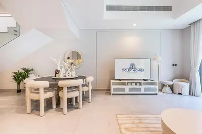 a living room with a table and a tv at Lovely Duplex Townhouse minutes from Downtown in Dubai