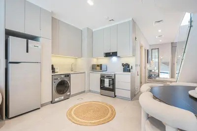 a kitchen with a washer and dryer and a table at Lovely Duplex Townhouse minutes from Downtown in Dubai