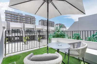 a patio with a table and chairs and an umbrella at Lovely Duplex Townhouse minutes from Downtown in Dubai