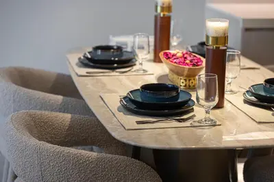 a table with plates and glasses and a bowl of flowers at Luxury 1 BHK in Jumeirah Village Circle BydPie Concept 302 in Dubai