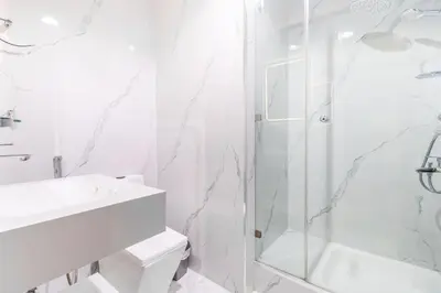 a white bathroom with a shower and a sink at Lux 3BHK in Dubai Marina with Marina View DEC 1306 in Dubai