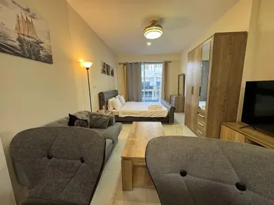 a living room with a couch and a bed at Furnished Studio in JVC Hassle-Free Living in Dubai