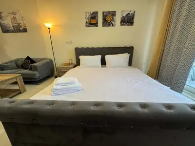 a bedroom with a large bed with a leather couch at Furnished Studio in JVC Hassle-Free Living in Dubai