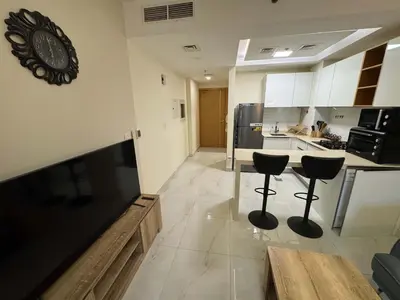 a kitchen with two bar stools and a clock on the wall at Furnished Studio in JVC Hassle-Free Living in Dubai